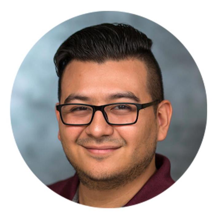 A close up headshot of a man with glasses